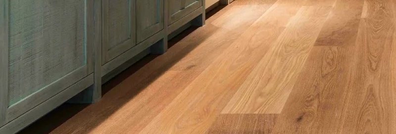 Rich brown wood-look Mohawk engineered hardwood floors add coziness to a living room with white and light beige décor.
